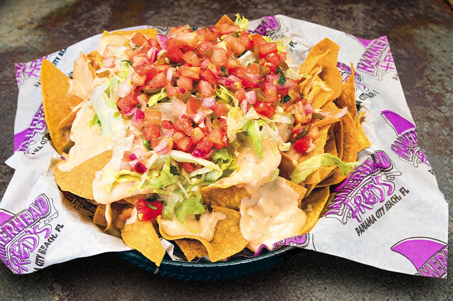 Chips Smothered in Fred’s Famous Queso Cheese Sauce made with Andouille Sausage, Green Chilies & Monterey Jack Cheese, Lettuce and Pico de Gallo